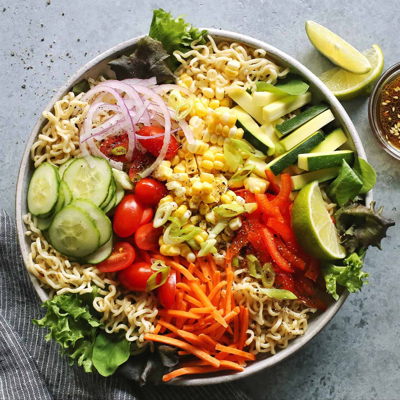 light gray bowl filled with ramen noodles and a variety of fresh vegetables