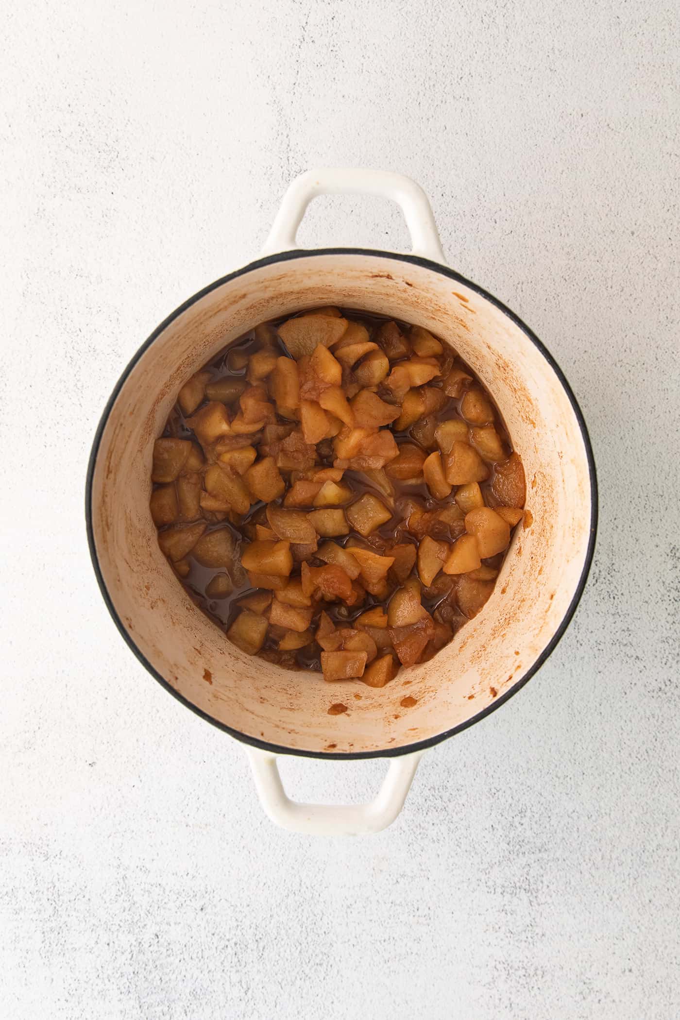 chopped apples cooked and softened in a large white pot