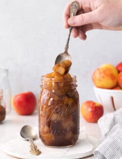 spooning into a jar of homemade applesauce