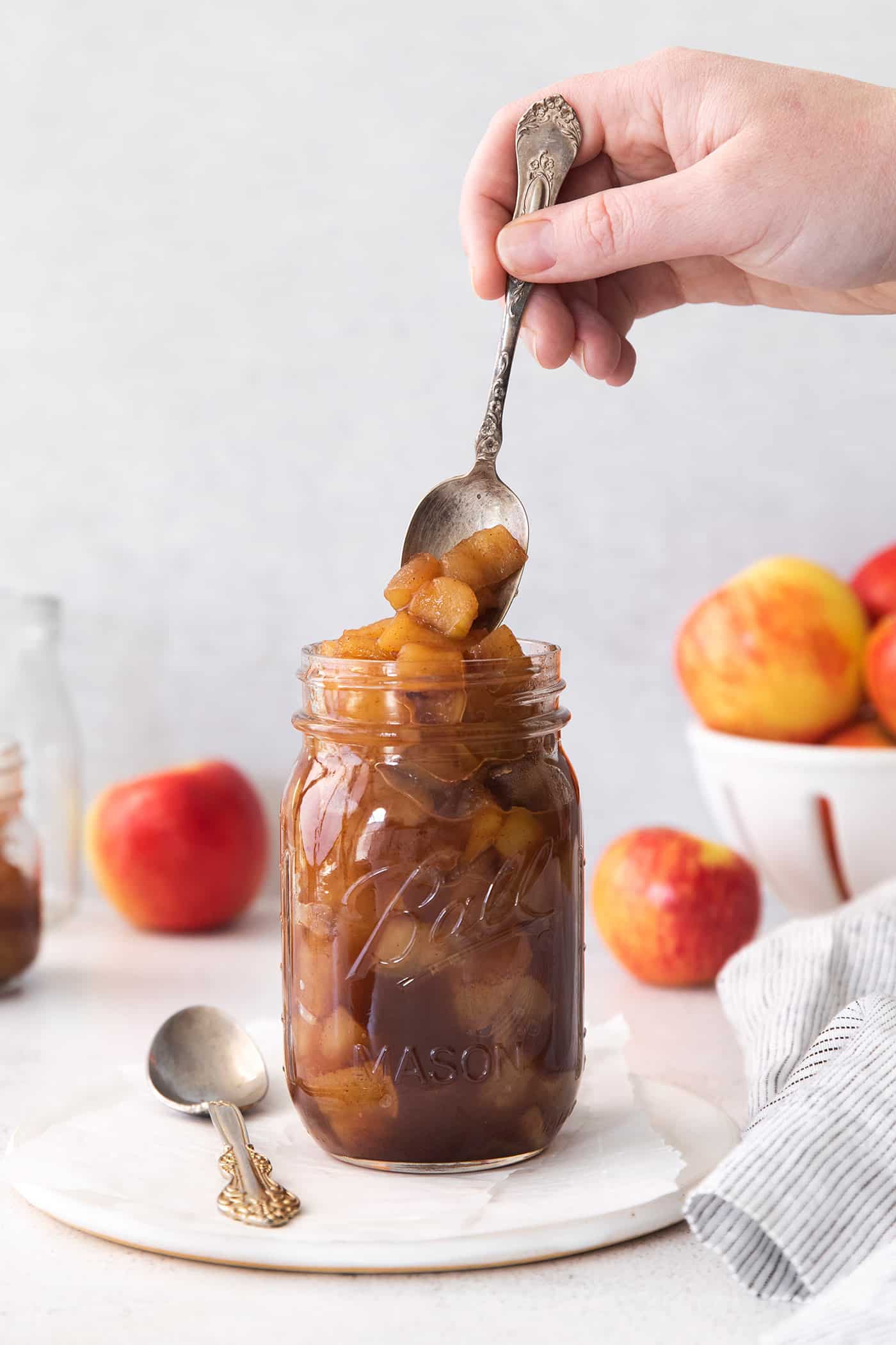 spooning into a jar of homemade applesauce