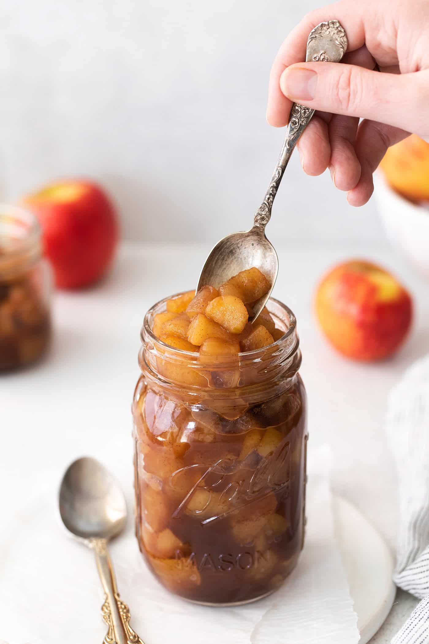 a spoon dipping into a jar of homemade applesauce