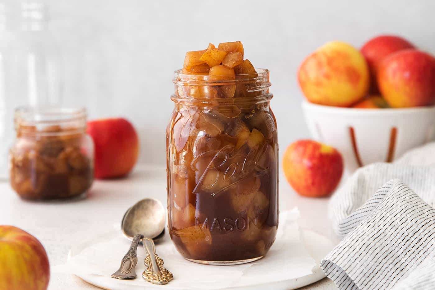 a jar of homemade chunky applesauce, surrounded by fresh apples