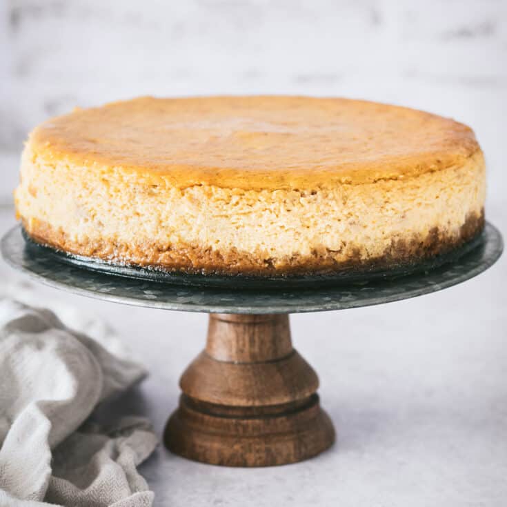 Pumpkin cheesecake on a wooden cake stand.