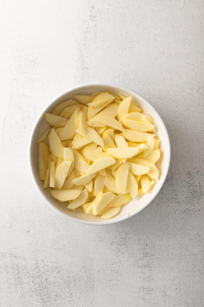sliced apples in a round white baking dish
