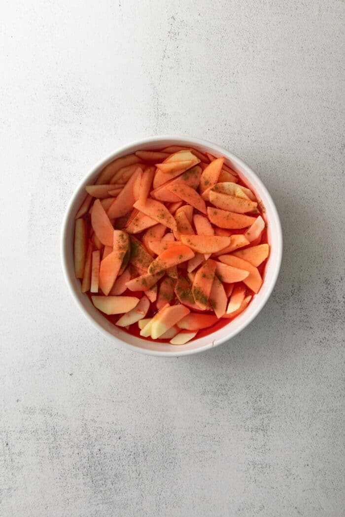 sliced apples covered in a red syrup and sprinkled with cinnamon