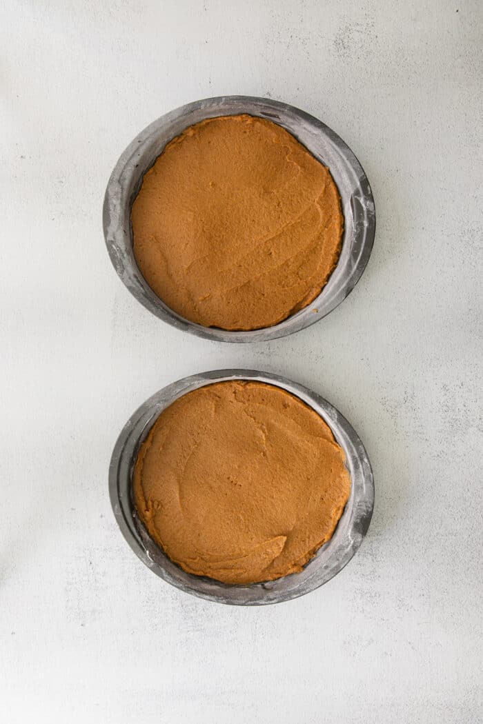 pumpkin cake batter divided between two round cake pans