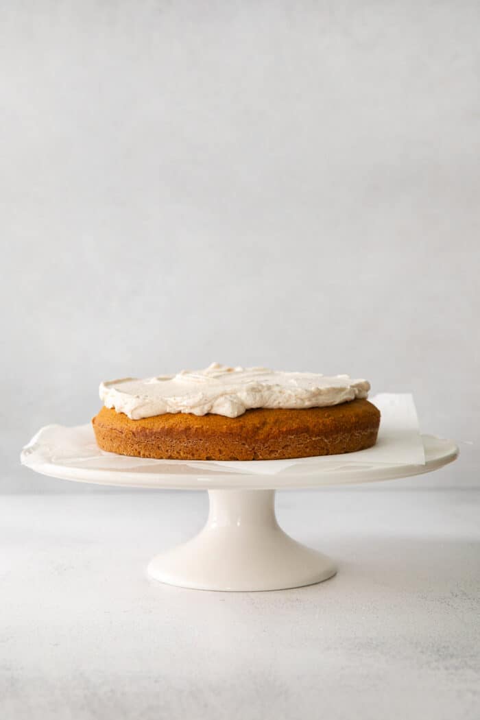 1 layer of pumpkin cake topped with creamy cinnamon whip, on a cake stand