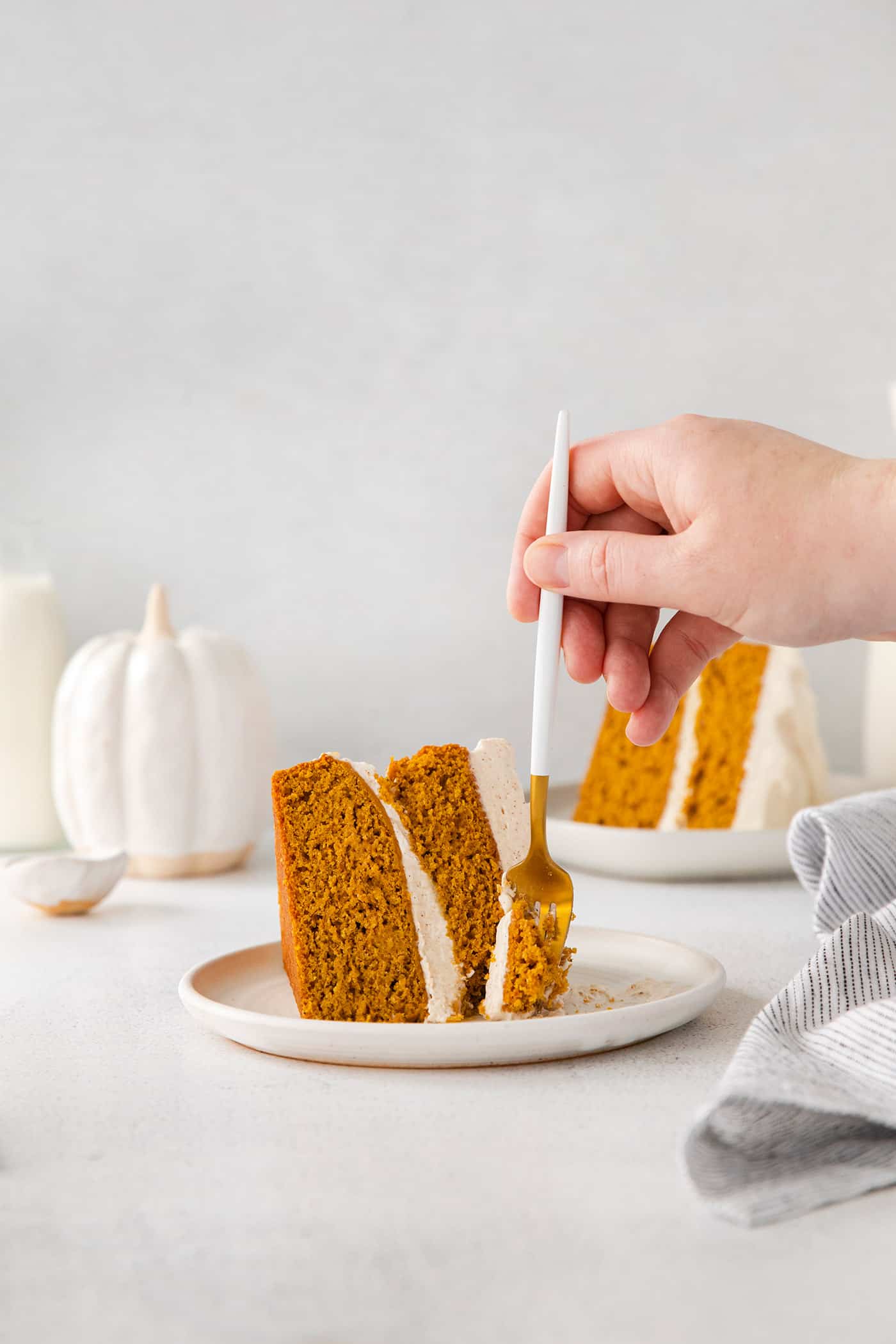 taking a forkful of pumpkin layer cake from an individual slice of cake on a plate
