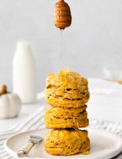 a stack of pumpkin biscuits with honey drizzled over them