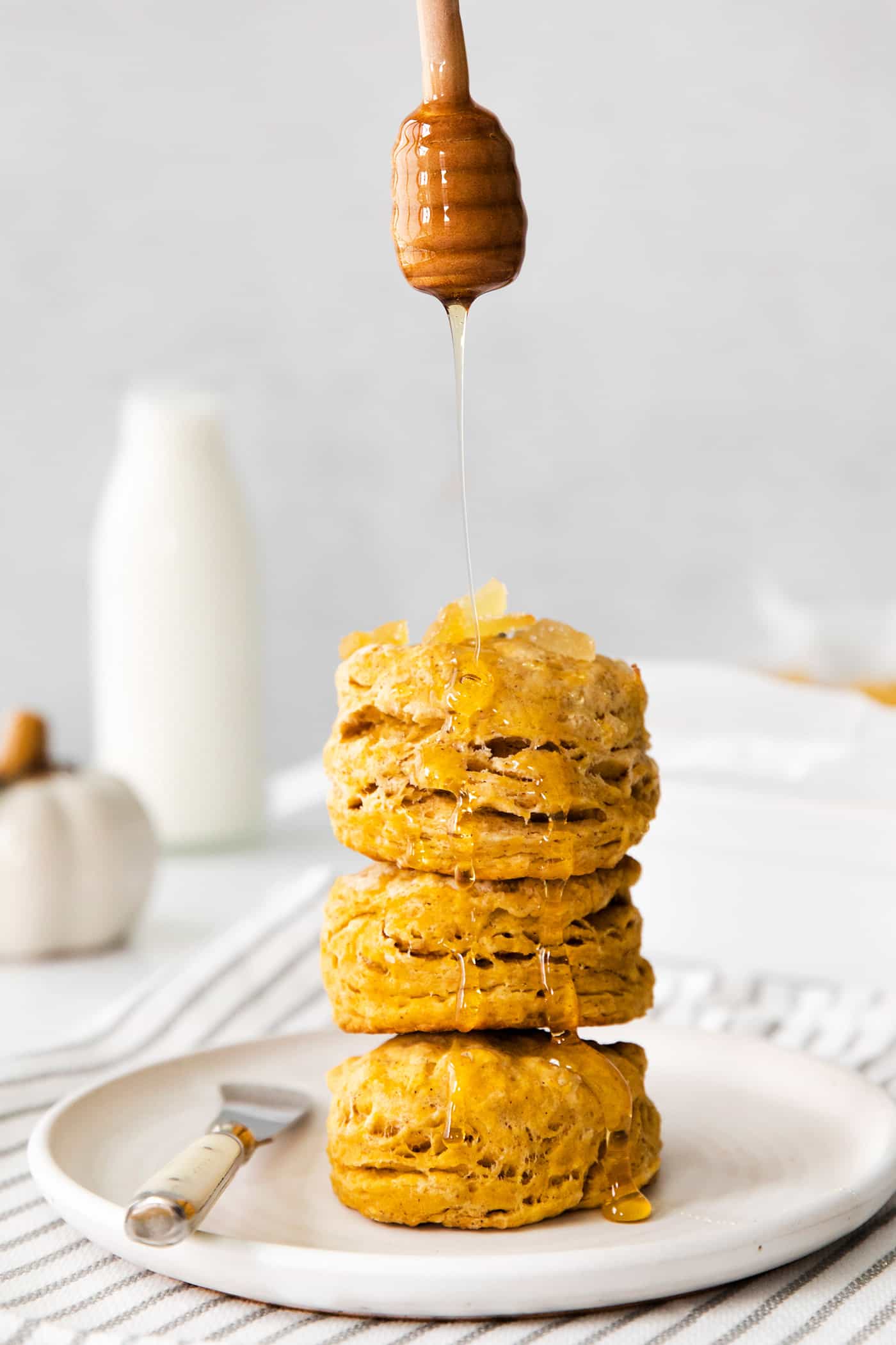 a stack of pumpkin biscuits with honey drizzled over them