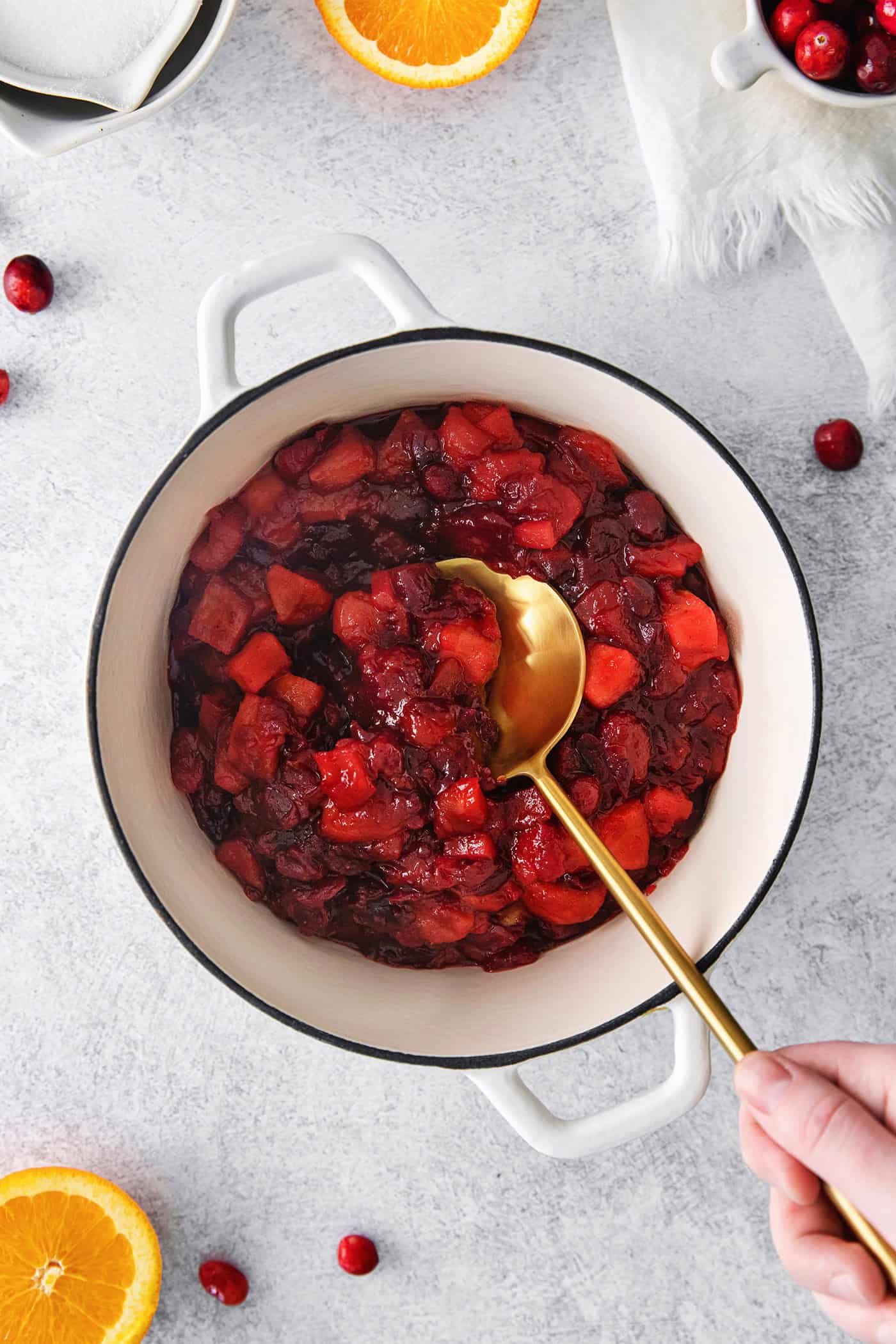 a white pot of homemade cranberry sauce, with a large gold spoon