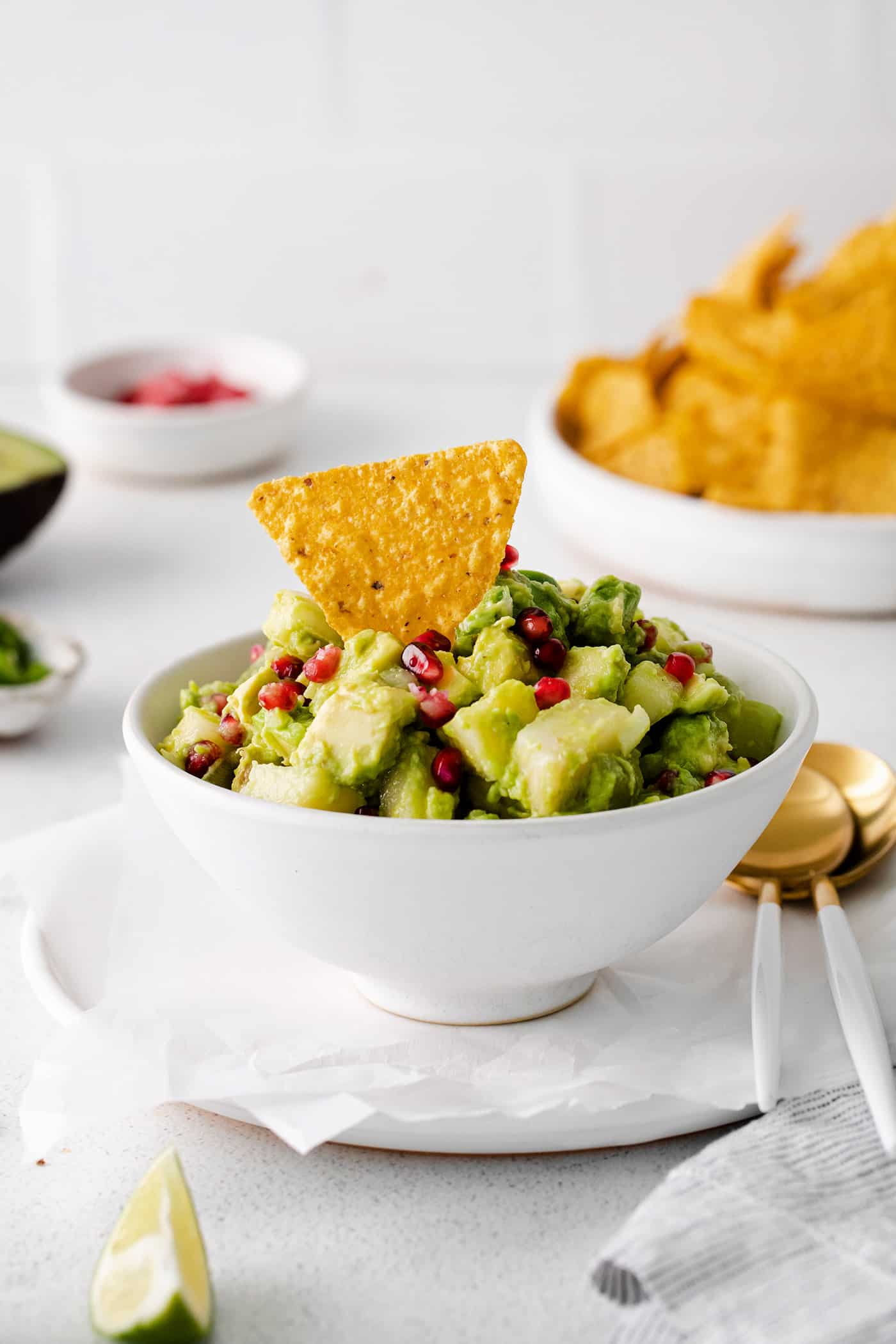 A bowl of pomegranate guacamole with a tortilla chip