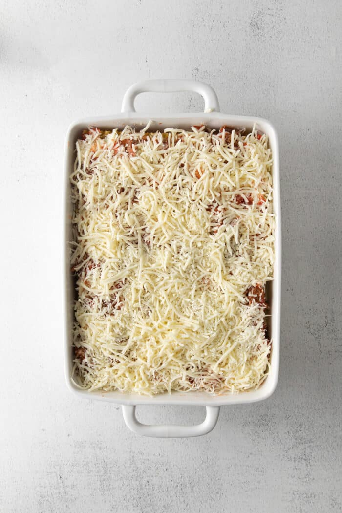 Lasagna topped with shredded mozzarella ready to be baked