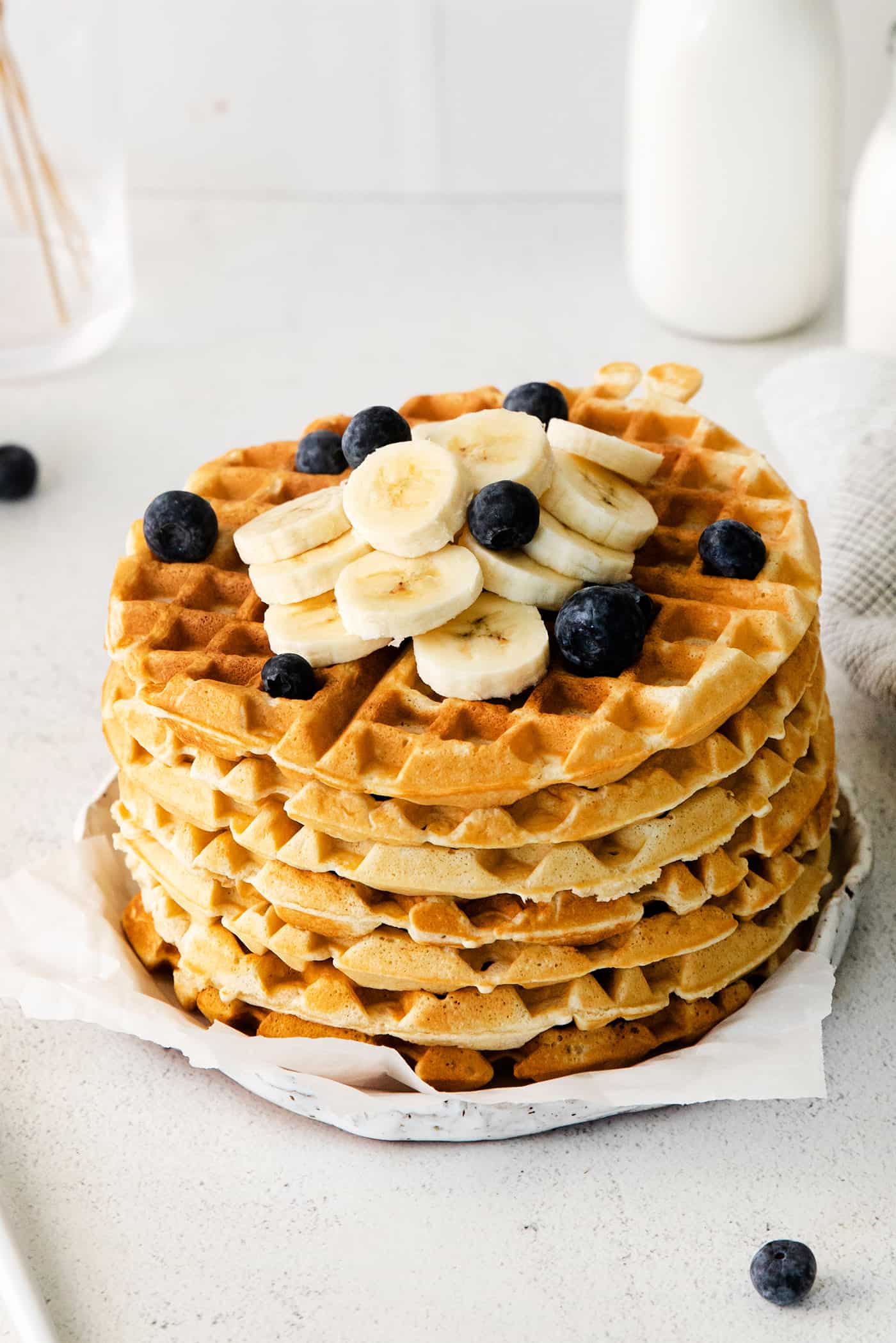 Angled view of a stack of homemade waffles with fresh fruit on top