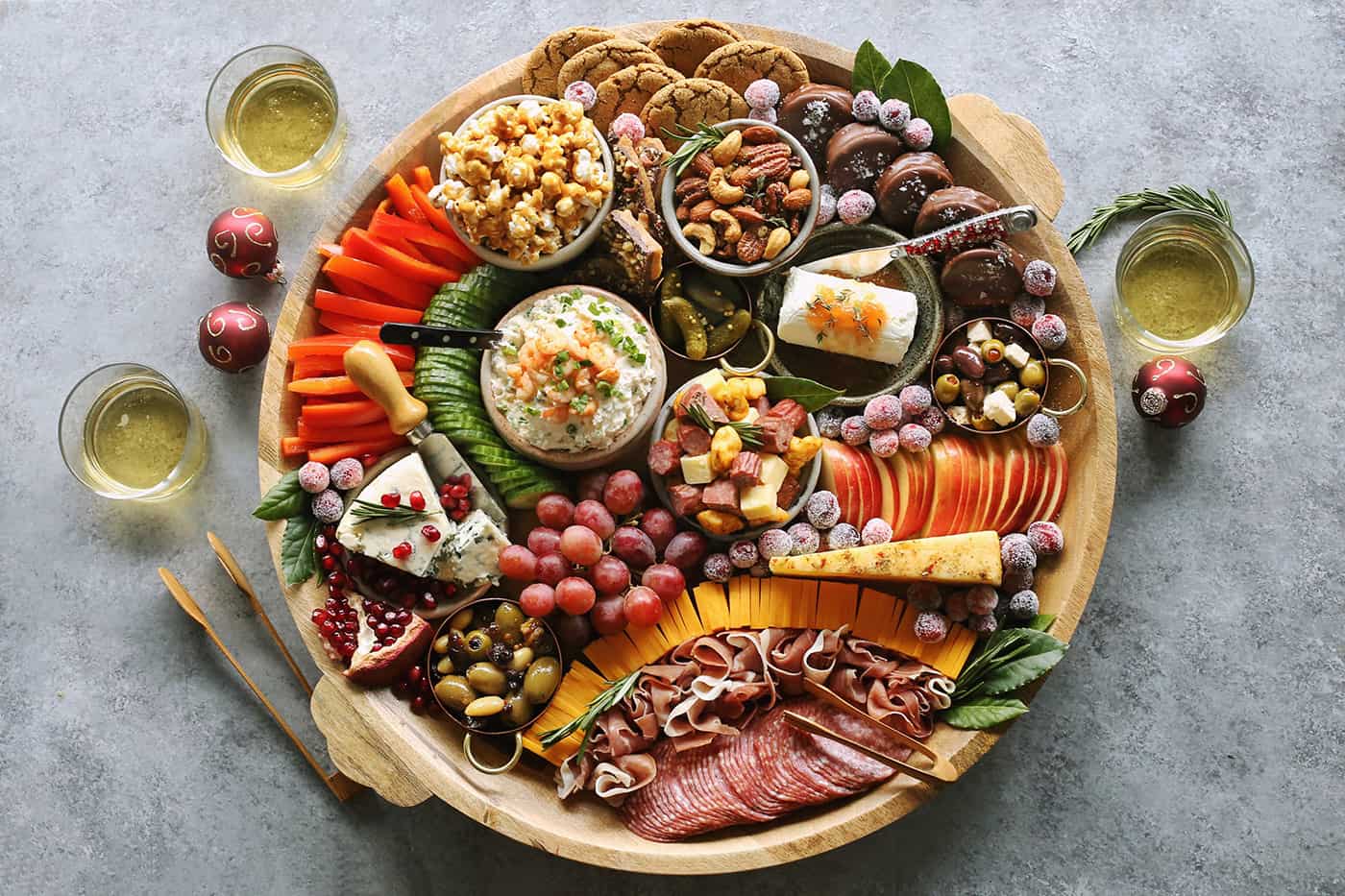 a large round wood charcuterie board full of meats, cheeses, and other nibbles