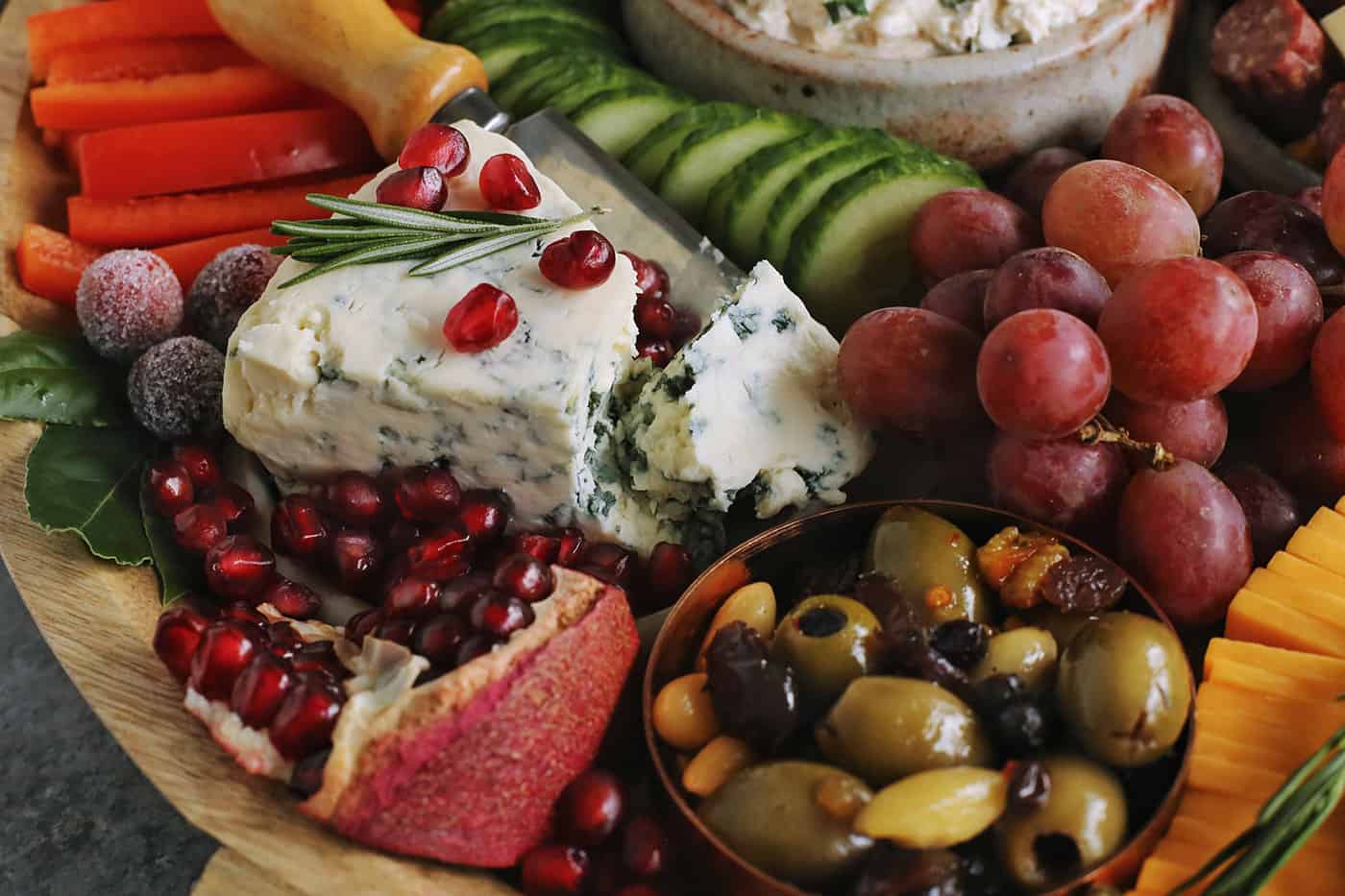 a wedge of blue cheese, pomegranate seeds, olives, grapes