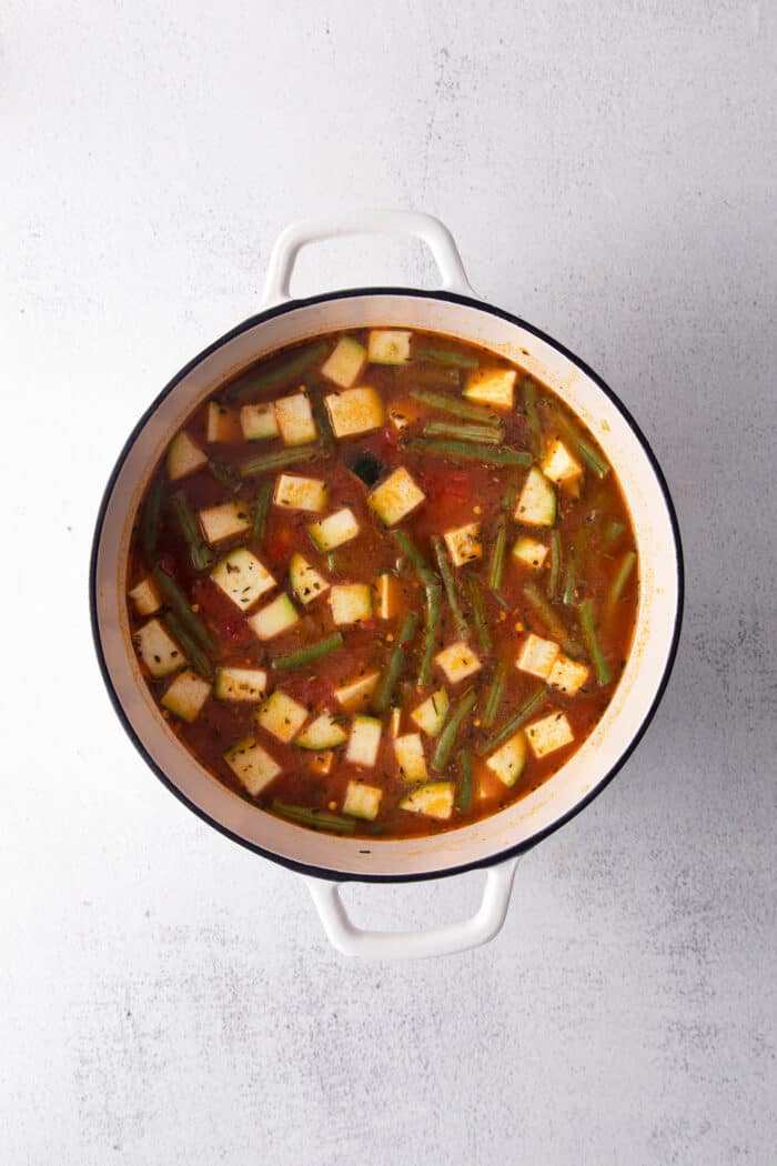 Vegetables, tomato paste, and broth in a soup pot