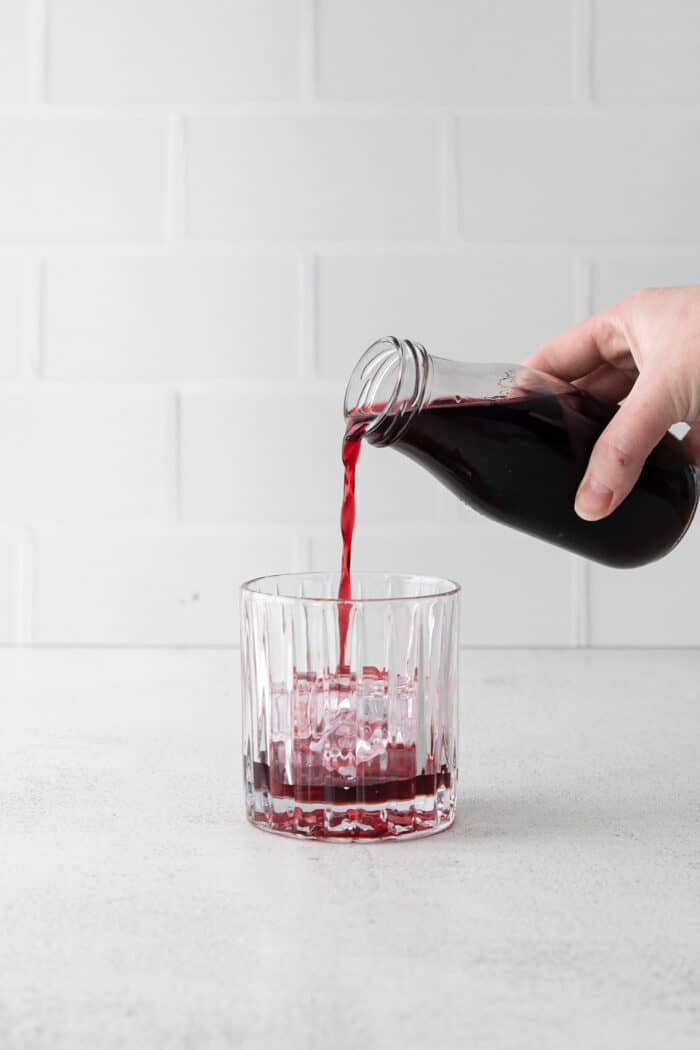 A hand pouring pomegranate juice into a glass