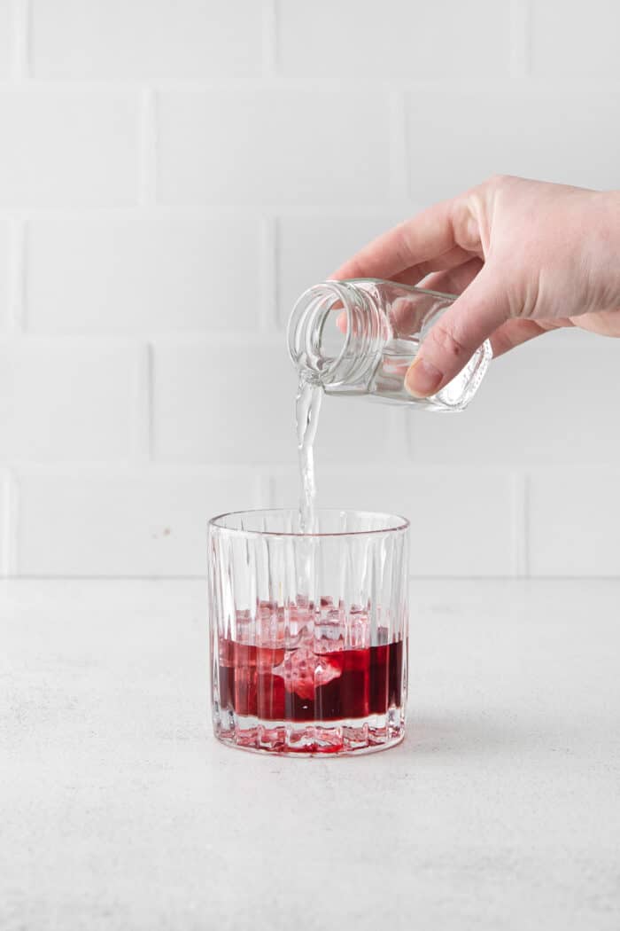 A hand pouring simple syrup into a glass