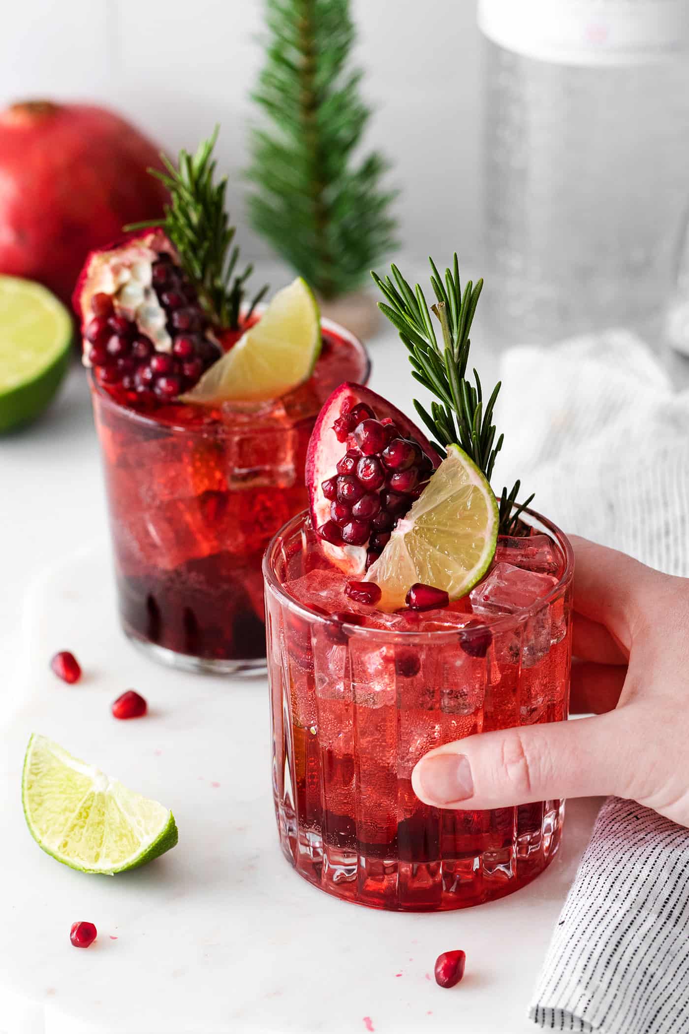 A hand reaching for a pomegranate gin and tonic