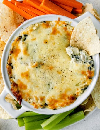 Overhead view of spinach artichoke dip surrounded by vegetables and chips