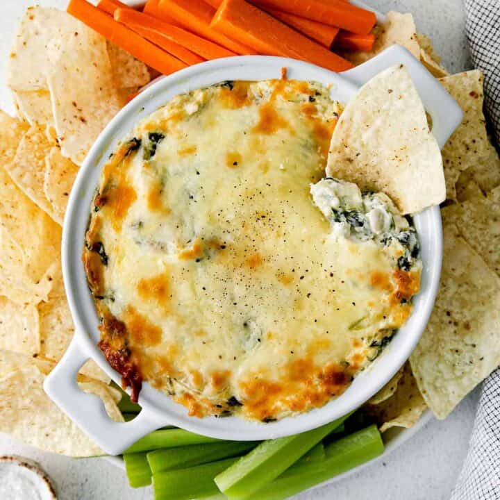 Overhead view of spinach artichoke dip surrounded by vegetables and chips