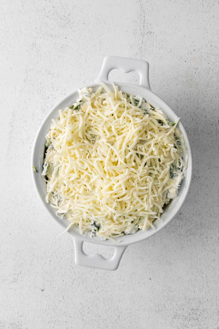 Spinach and artichoke dip in a dish topped with mozzarella