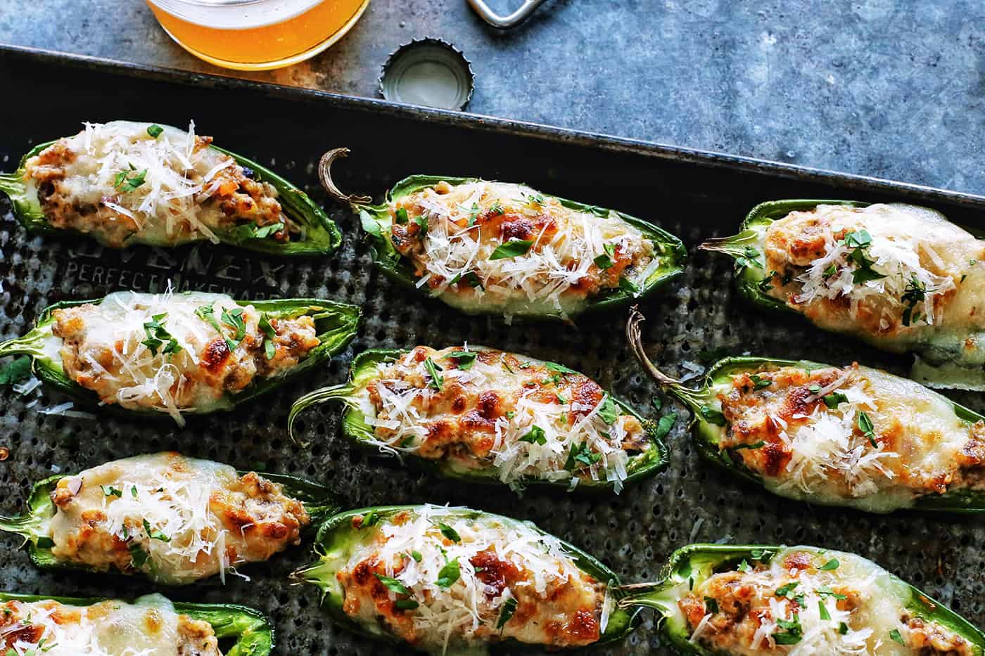 stuffed jalapeno peppers on a baking pan, plus a glass of beer