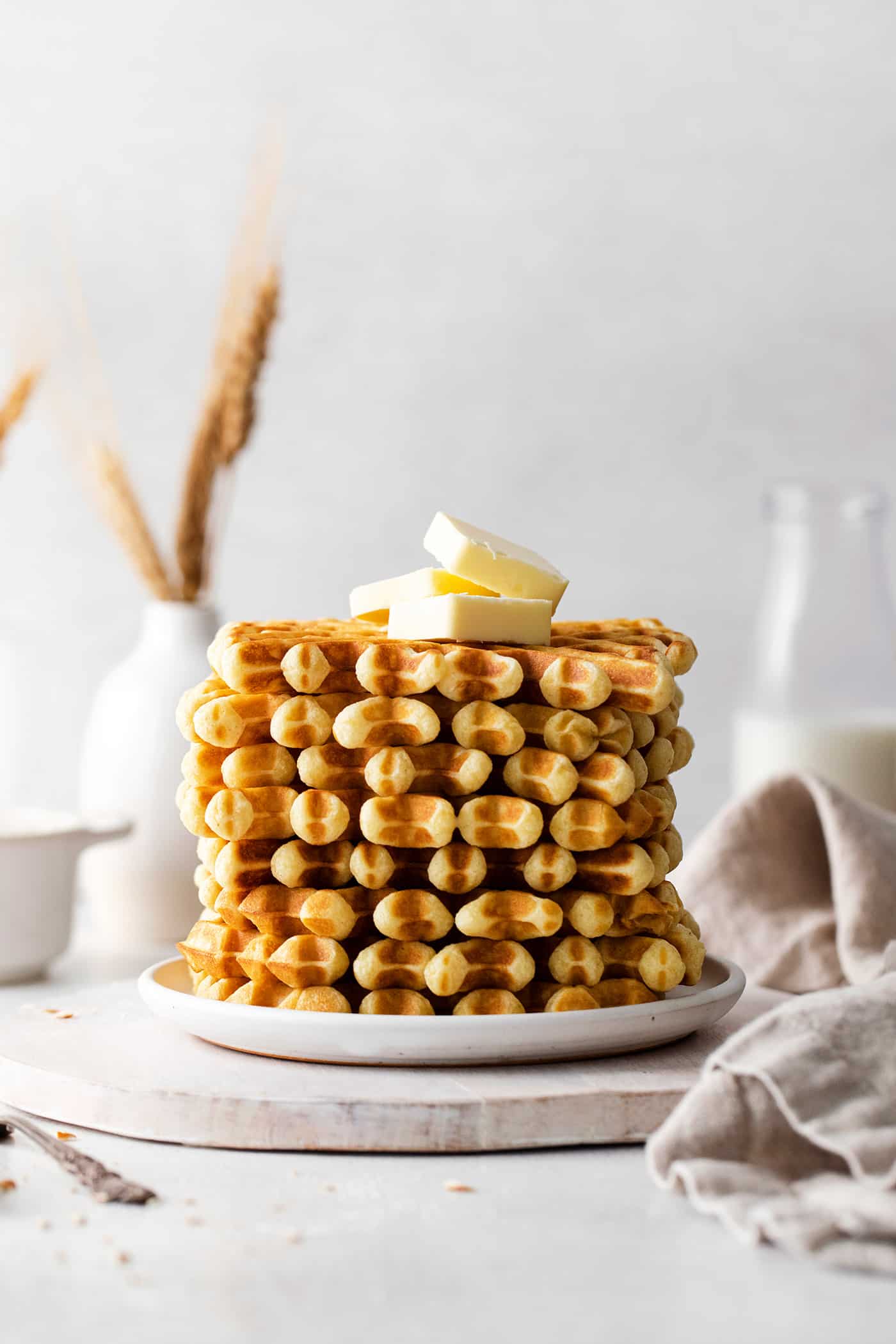 A stack of buttermilk waffles topped with butter