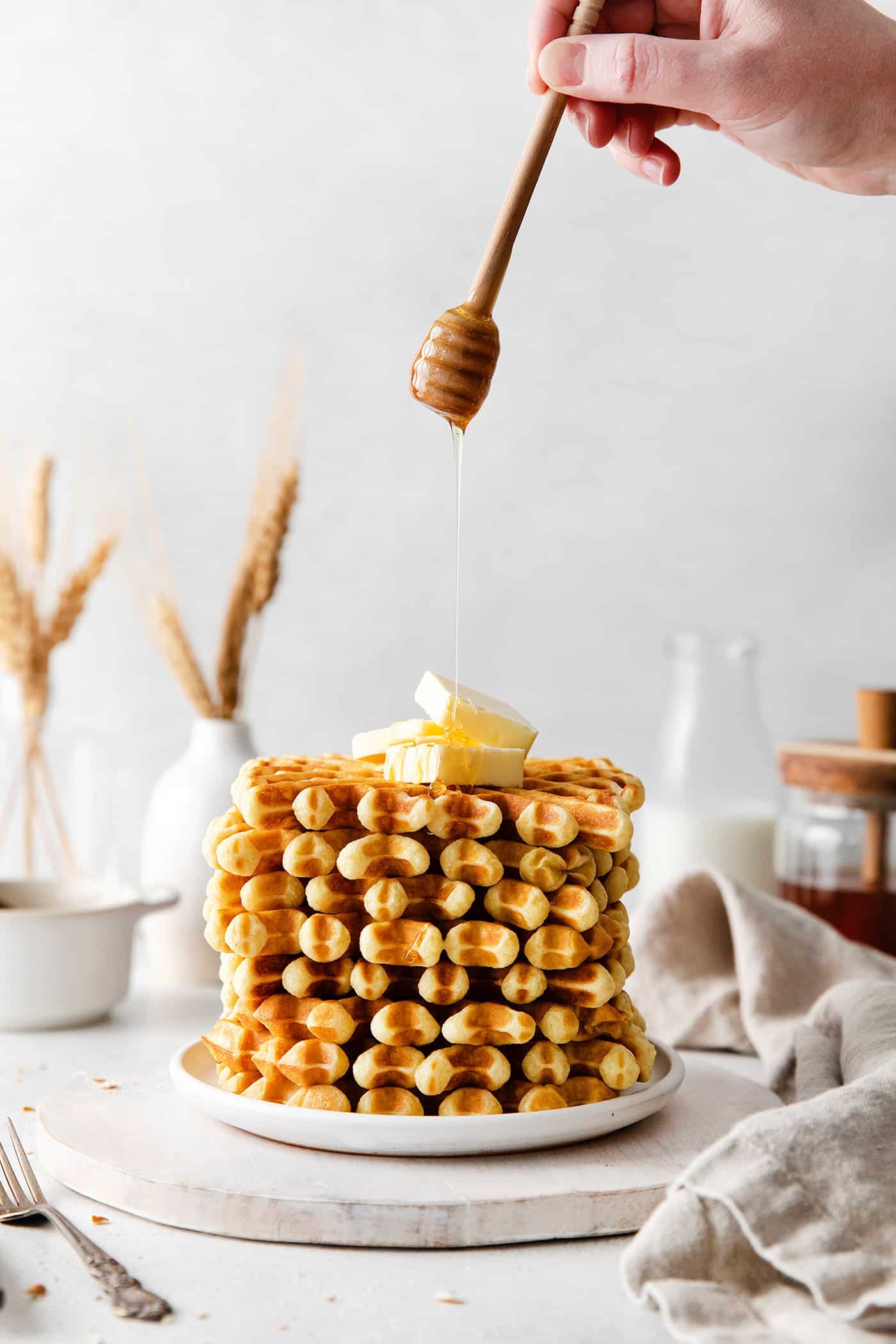 Honey being drizzled over the top of buttermilk waffles