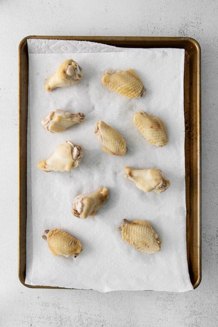 Parboiled wings on a baking sheet lined with paper towels