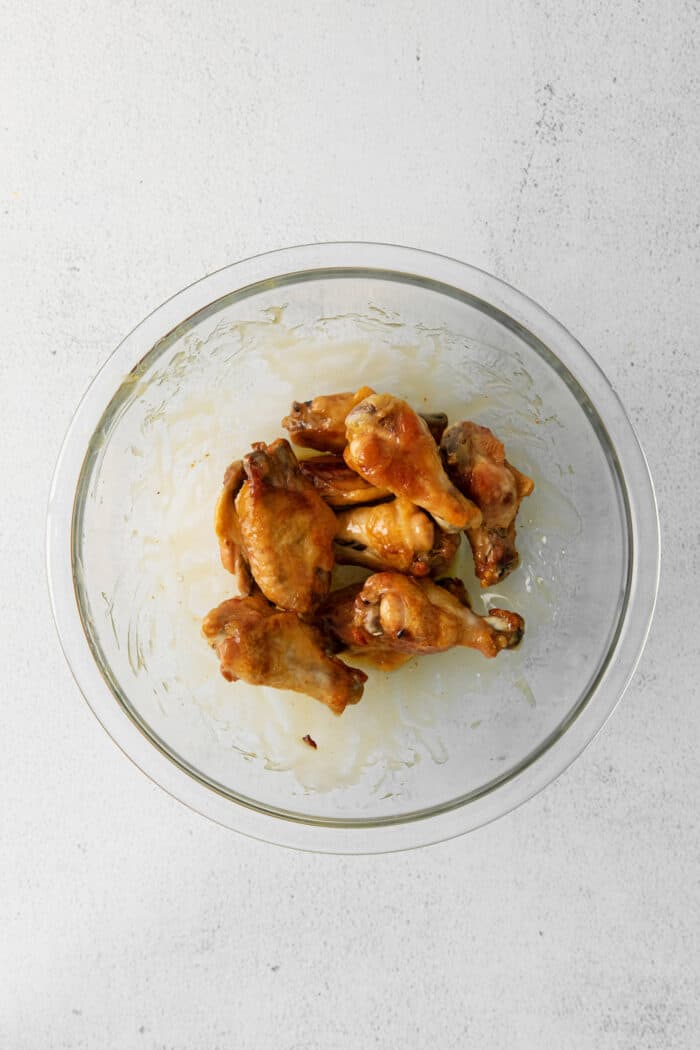 Crispy baked wings being tossed with hot honey sauce