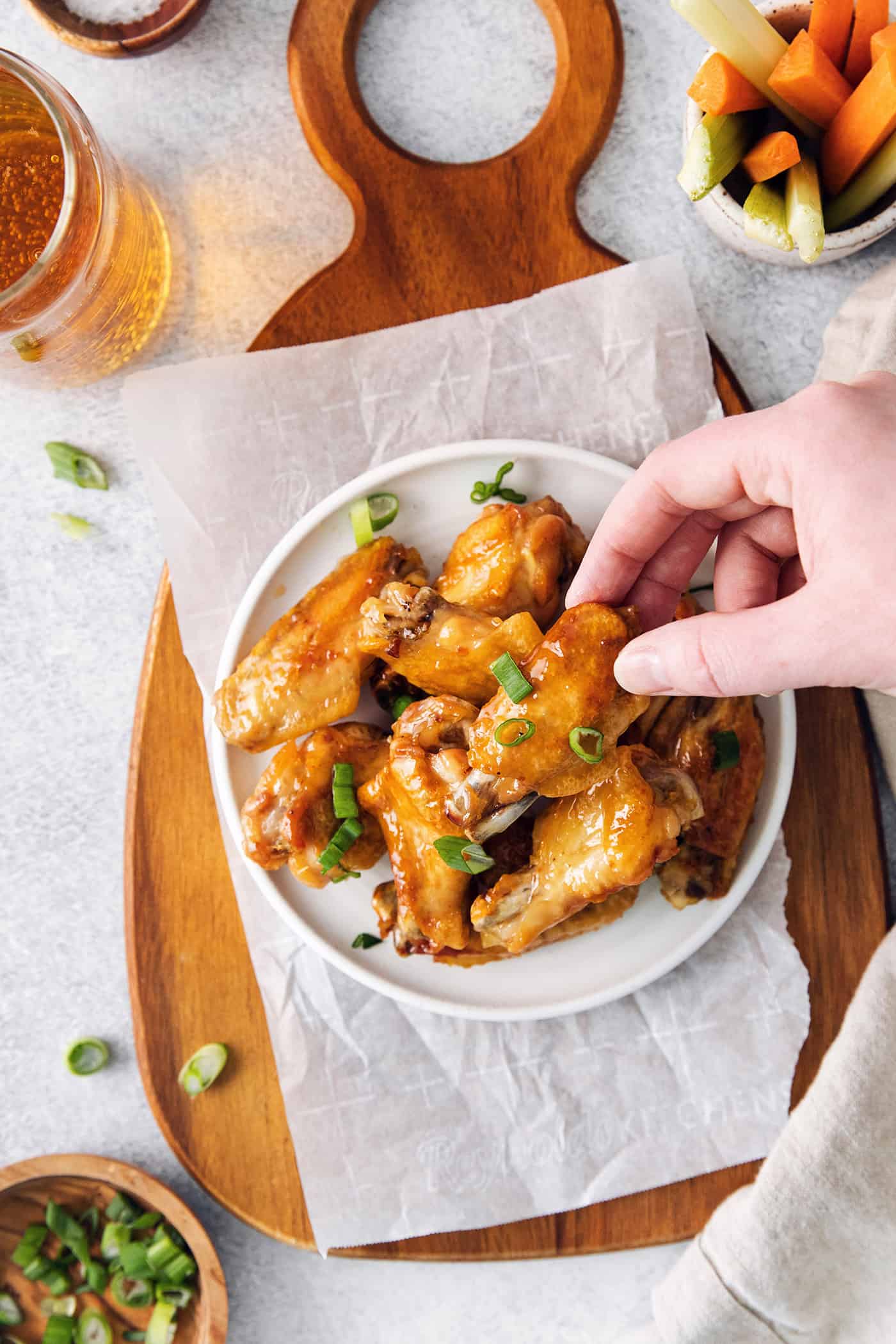 A hand grabbing a crispy baked chicken wing with hot honey sauce