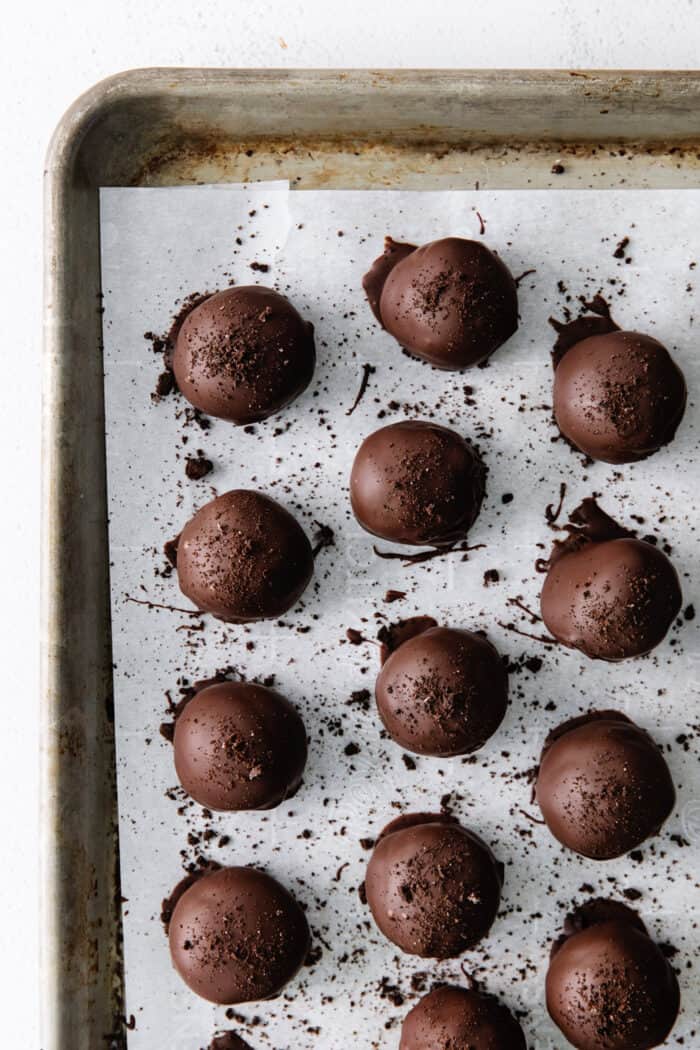 Oreo truffles dipped in chocolate on a baking sheet