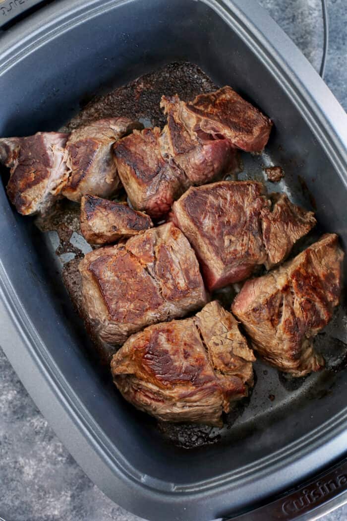 Pieces of chuck roast seared in a slow cooker