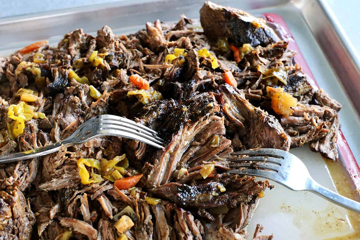 Italian beef being shredded with two forks