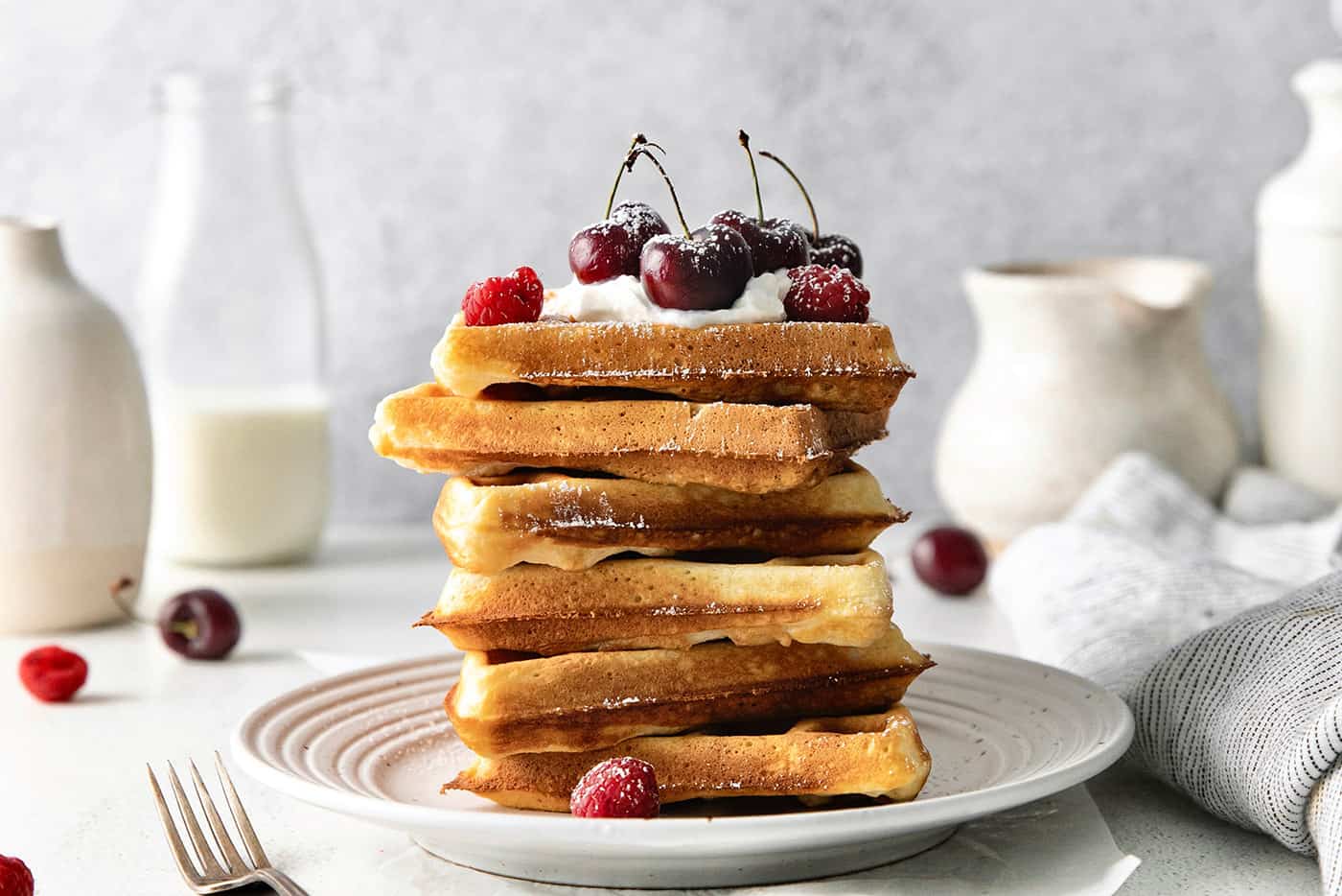 A stack of Belgian waffles topped with cherries