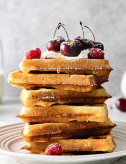 A stack of homemade waffles topped with cherries