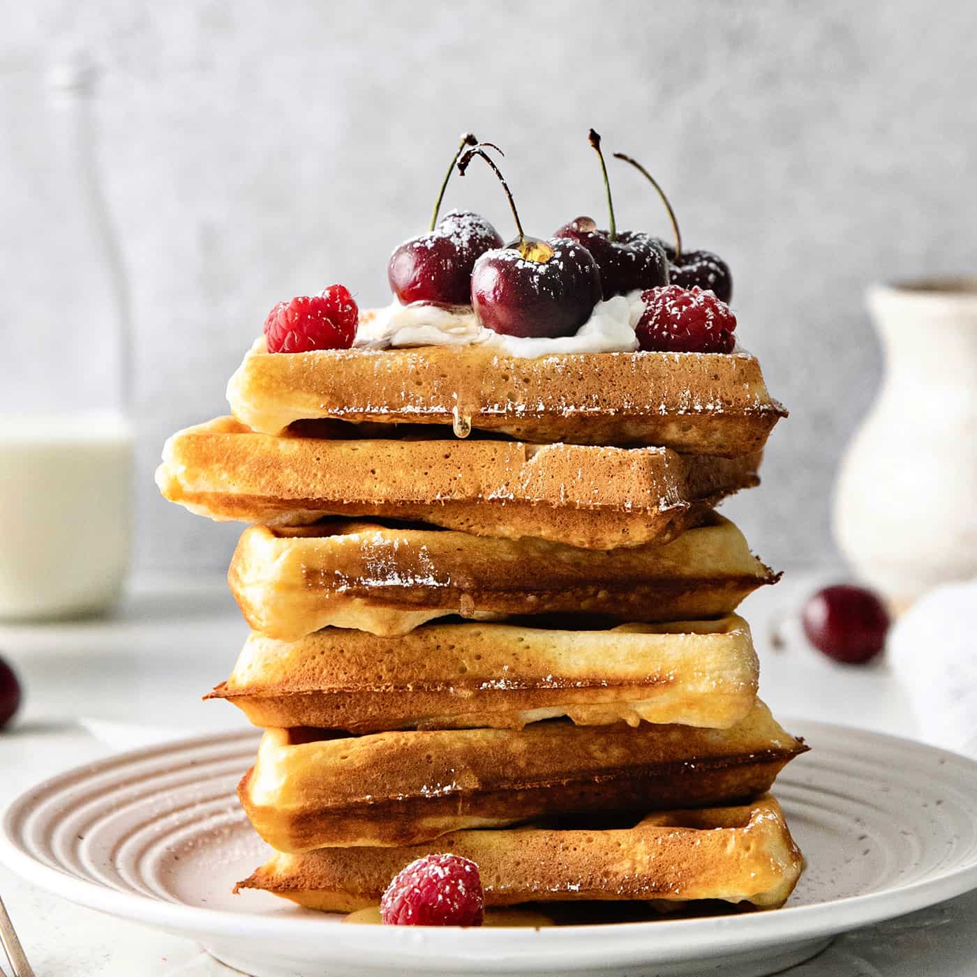 A stack of homemade waffles topped with cherries