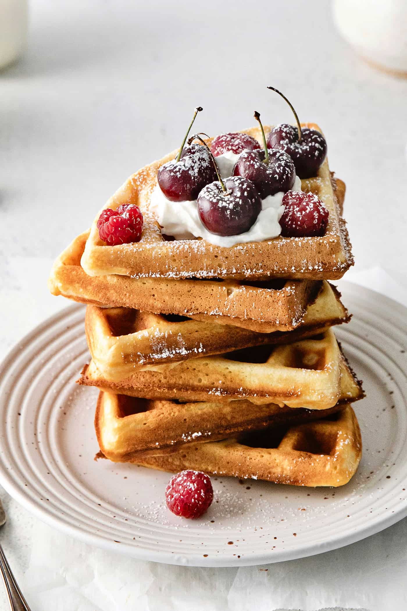 Angled view of a stack of waffles topped with cherries