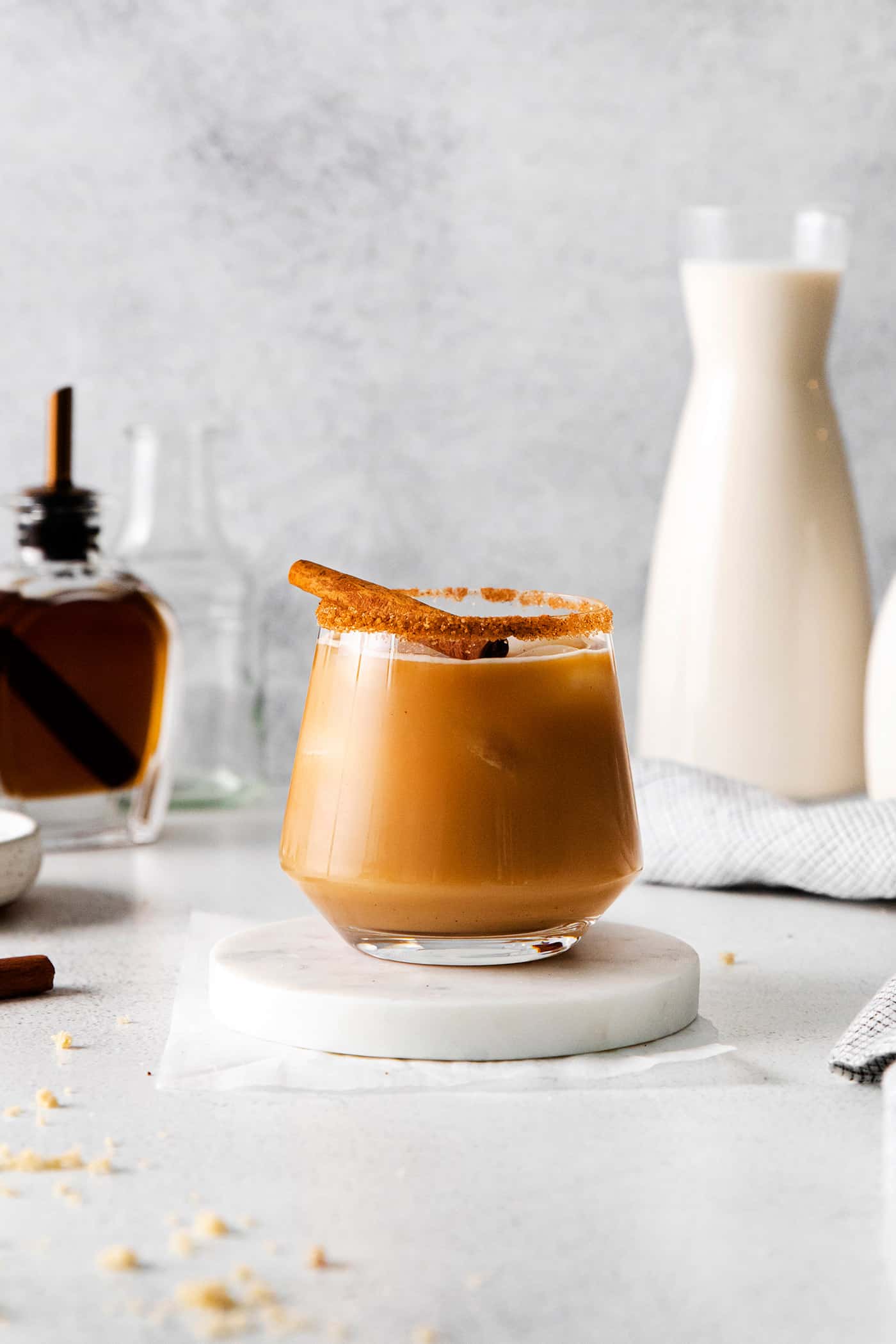 an eggnog white Russian cocktail in a glass rimmed with cinnamon sugar