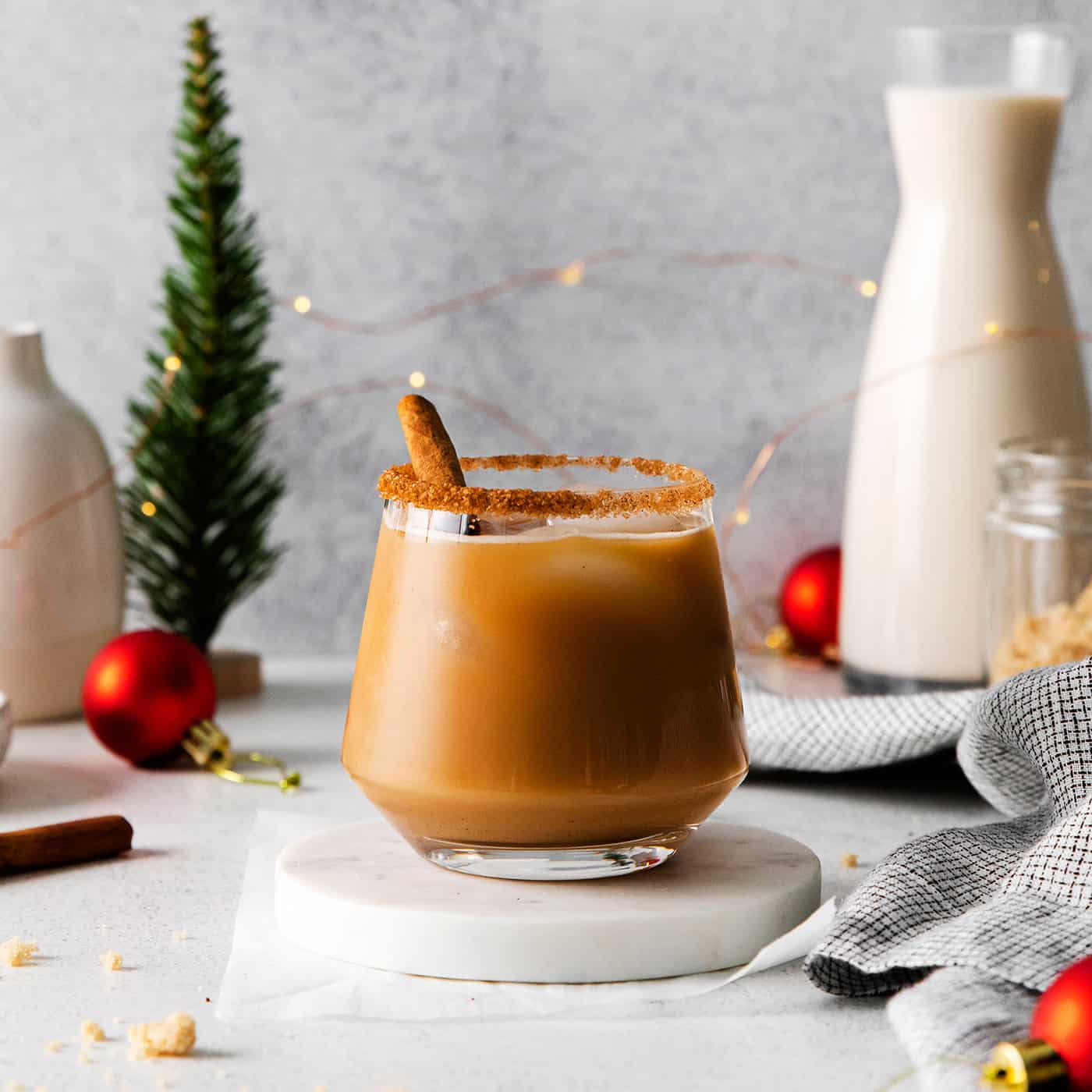 a white Russian cocktail with eggnog and cinnamon syrup, plus Christmas decorations