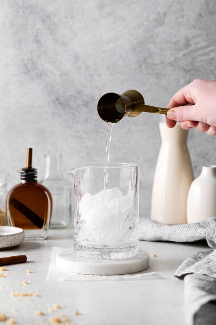 pouring vodka over ice in a cocktail glass