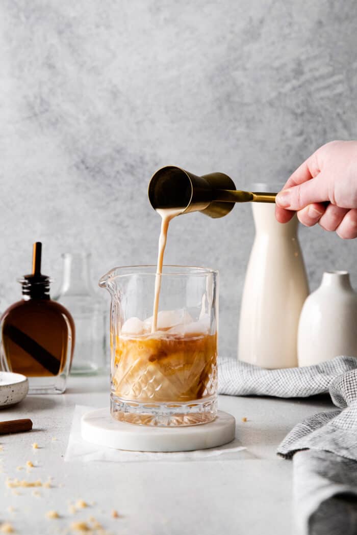 pouring eggnog into a cocktail glass