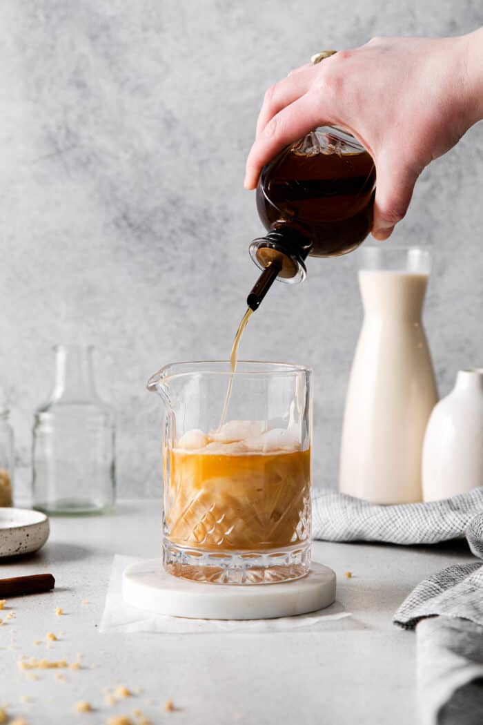 pouring cinnamon syrup into a cocktail glass