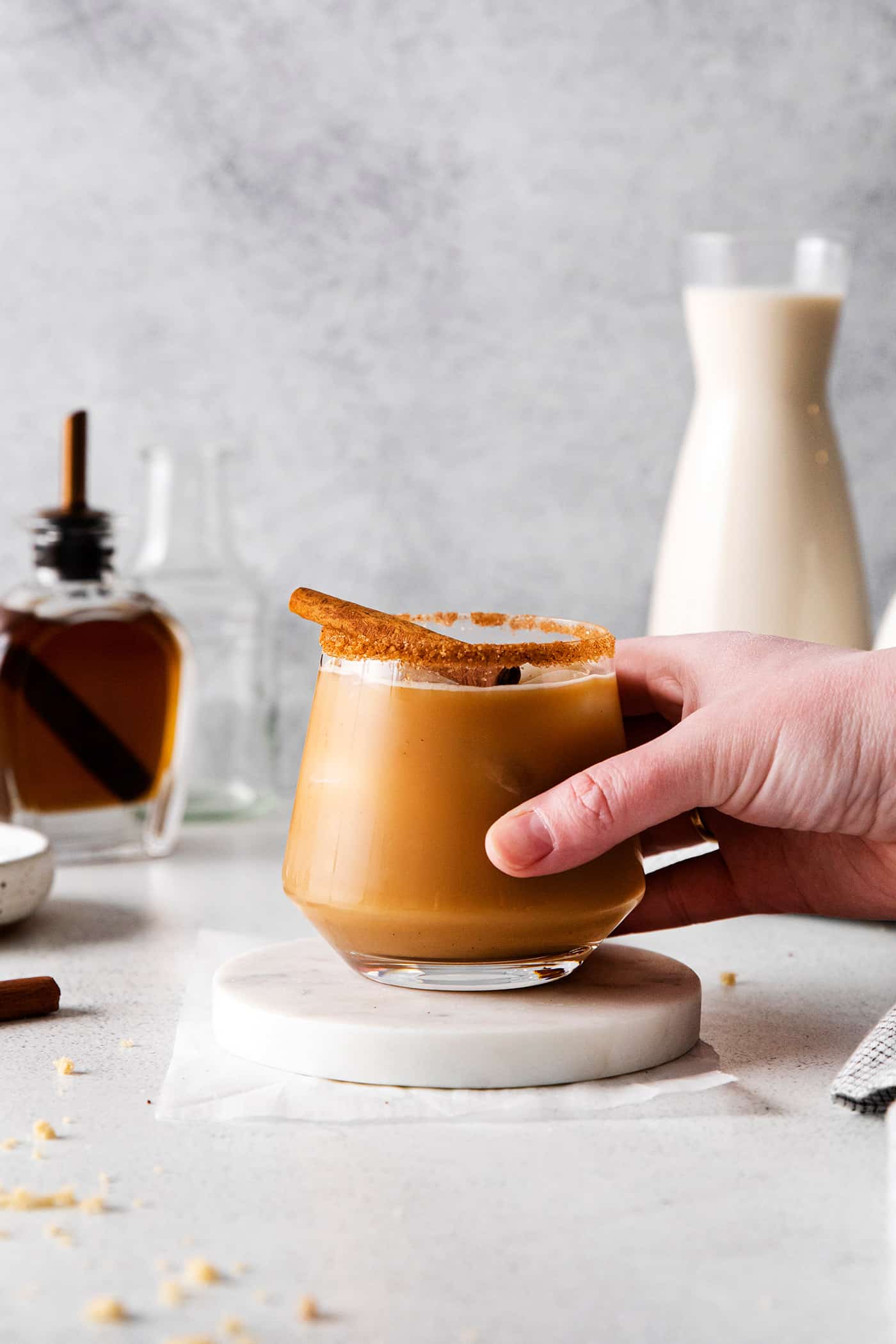 a hand holding a glass of cinnamon spiced eggnog white Russian cocktail