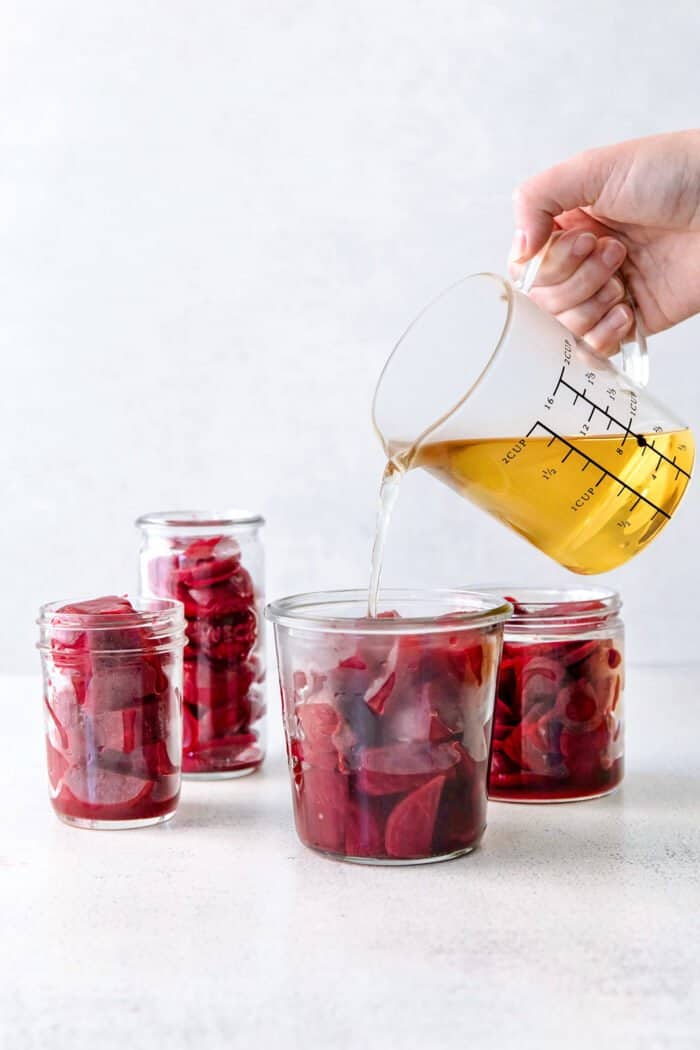 pouring pickling brine over a jar of cubed beets