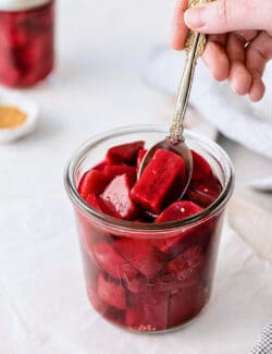 dipping a spoon into a jar of pickled beets