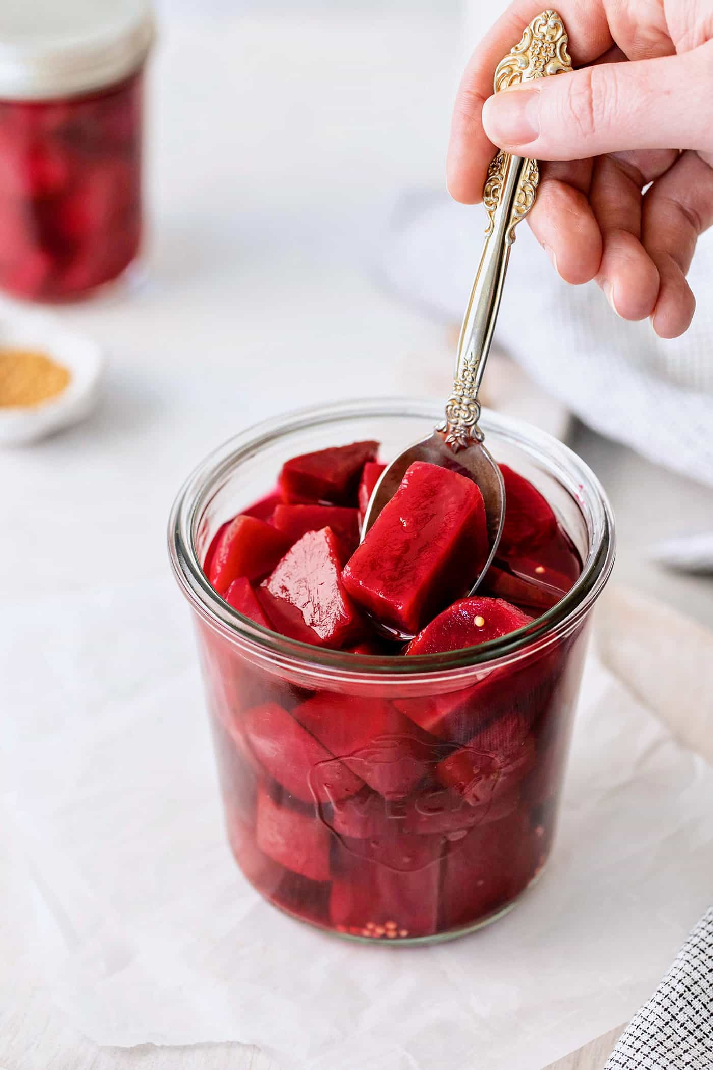 dipping a spoon into a jar of pickled beets