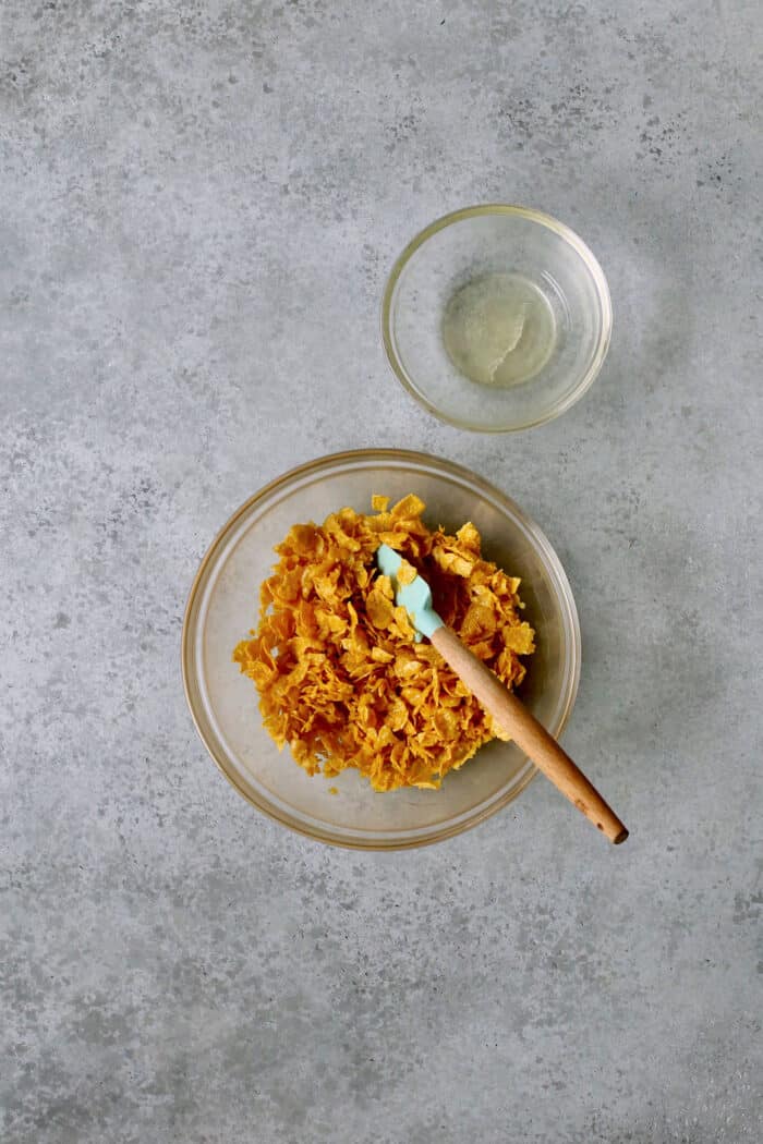 Crushed cornflakes mixed with butter in a small bowl